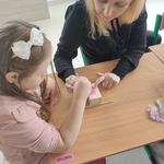 Nauczycielka pomaga uczennicy przyklejać ozdoby