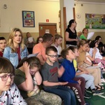 Uczniowie siedzący na ławeczkach.