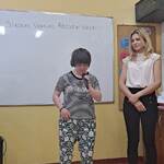 Uczennica mówi wiersz do mikrofonu. Obok stoi nauczycielka.