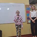 Uczennica mówi wiersz do mikrofonu. Obok stoją nauczycielki.