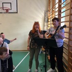 Nauczycielki śpiewają do mikrofonów, Jedna gra na gitarze.