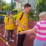 Uczeń odbiera puchar z rąk organizatorki. Za nim stoją uczniowie