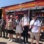 Grupa uczniów na tle wozu strażackiego.
