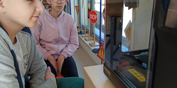 Uczniowie patrzą na drukarkę 3D